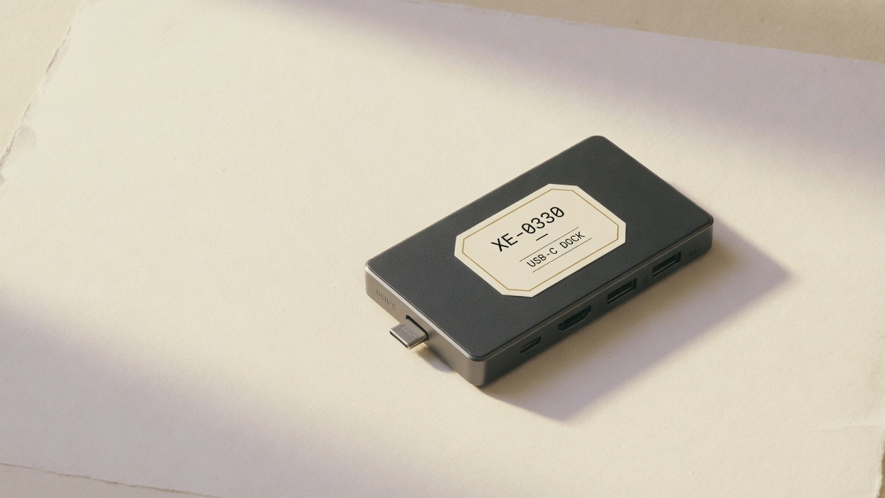 USB-C dock with asset tag XE-0330 on a paper backdrop