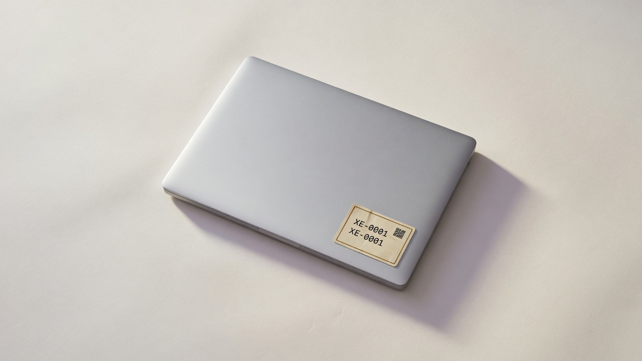 Tagged laptop XE-0001 on a paper backdrop
