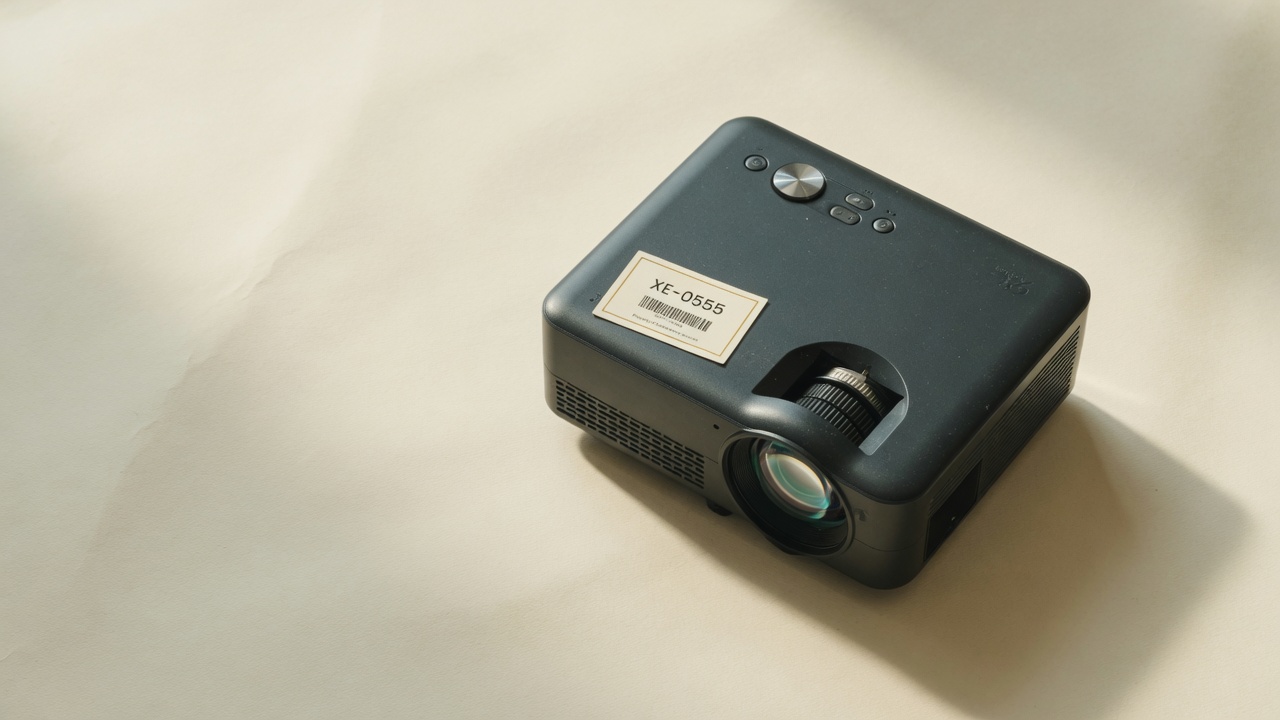 Conference projector with asset tag XE-0555 on a paper backdrop