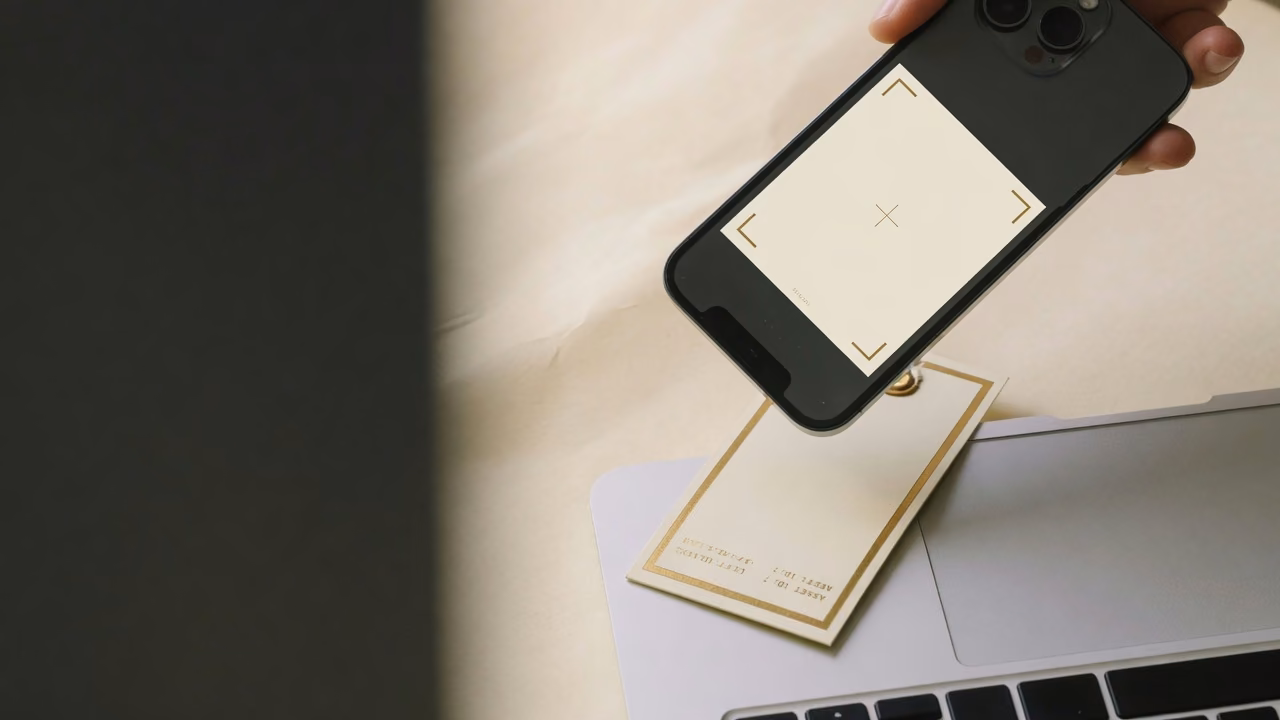 Phone scanning a cream asset label on a laptop